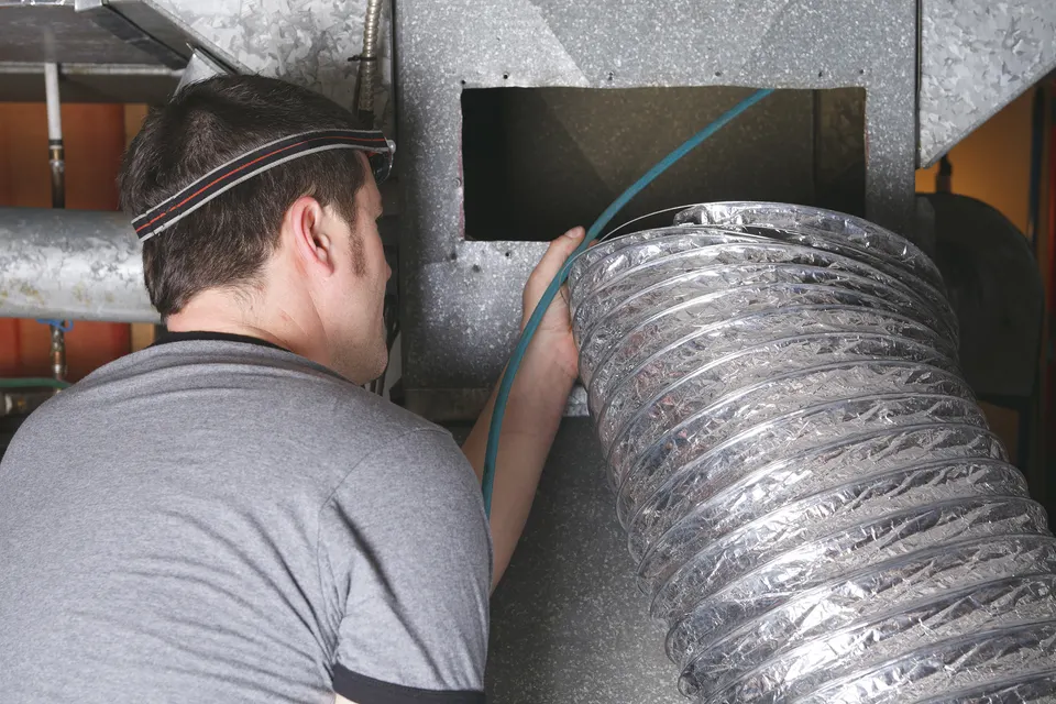 Technician cleaning a home air duct system