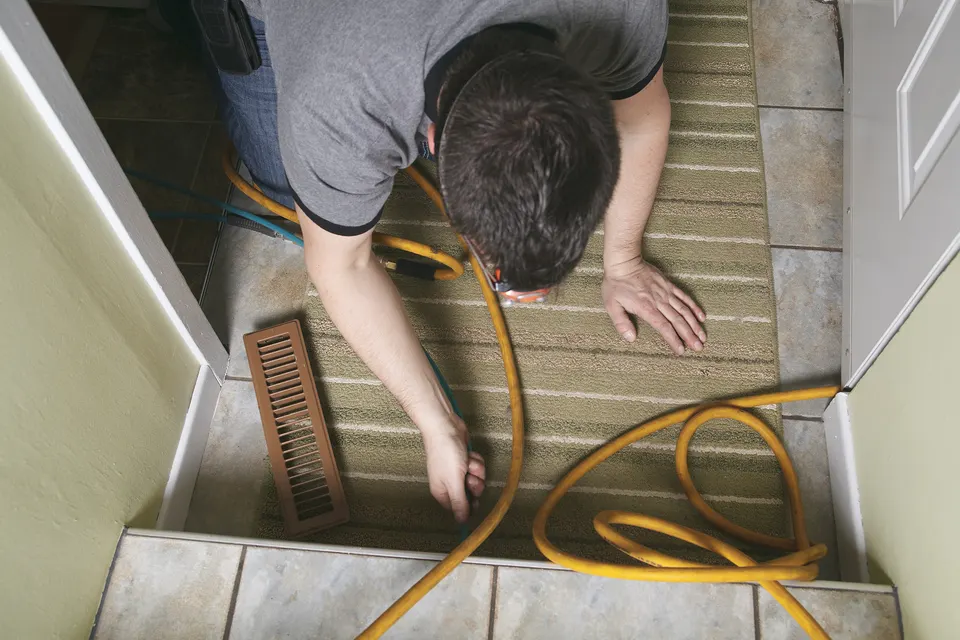 Technician vacuuming a floor register