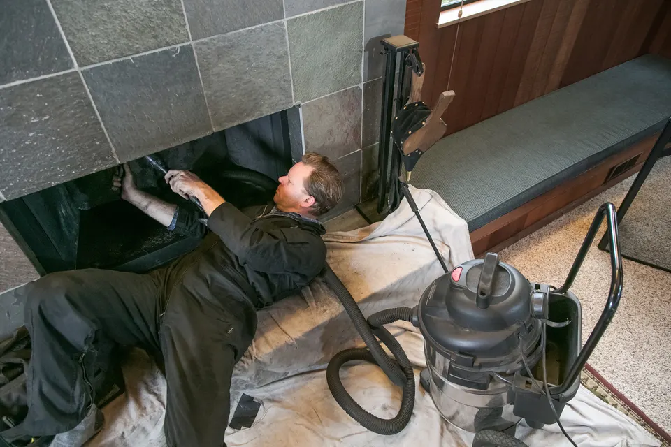 Chimney sweep technician working at a fireplace